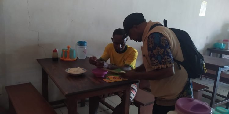 Seorang petugas kesehatan sedang memberikan edukasi tentang makanan higienis kepada seorang warga yang sedang makan di sebuah rumah makan di Dekai.