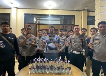 Kapolres Yahukimo didampingi Kasat lantas, dan anggota Polres lainnya saat memperlihatkan hasil sitaan botol miras.