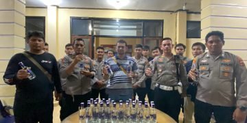 Kapolres Yahukimo didampingi Kasat lantas, dan anggota Polres lainnya saat memperlihatkan hasil sitaan botol miras.