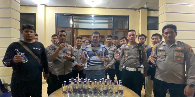 Kapolres Yahukimo didampingi Kasat lantas, dan anggota Polres lainnya saat memperlihatkan hasil sitaan botol miras.